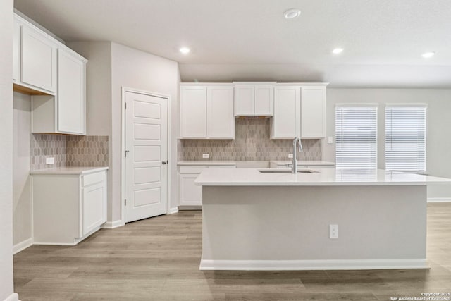 11538 Cottage Pt, San Antonio, TX 78254 - kitchen featuring a center island with sink, decorative backsplash, light wood-type flooring, white cabinetry, and recessed lighting