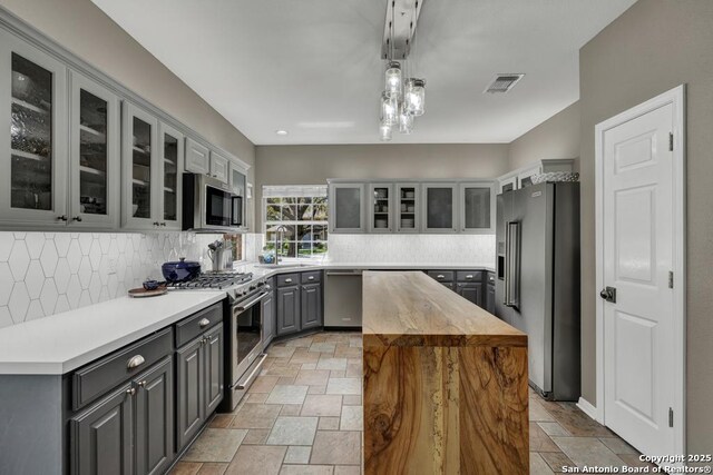 1780 Oak Frst, New Braunfels, TX 78132 - kitchen featuring visible vents, gray cabinets, a center island, high quality appliances, and stone tile flooring