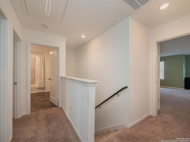 hallway featuring visible vents, carpet floors, attic access, an upstairs landing, and baseboards