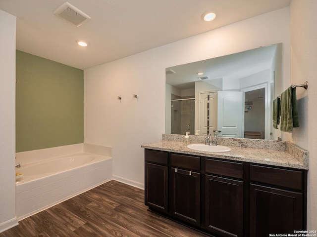full bathroom with vanity, a shower stall, visible vents, a garden tub, and wood finished floors