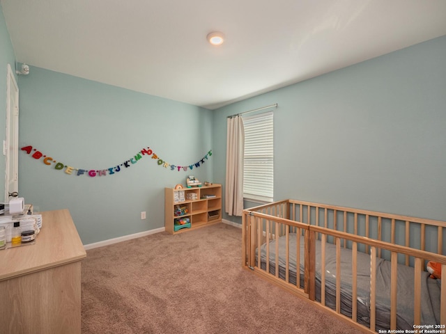 carpeted bedroom featuring baseboards and a nursery area