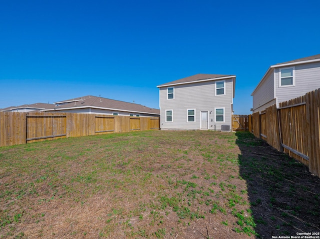 rear view of property with central air condition unit, a fenced backyard, and a lawn