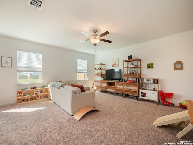 living room featuring carpet flooring, ceiling fan, and visible vents