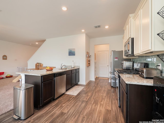 kitchen with light stone countertops, a peninsula, visible vents, a sink, and stainless steel appliances