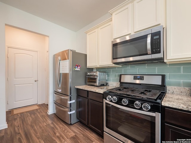 kitchen featuring dark wood finished floors, light stone counters, decorative backsplash, and stainless steel appliances