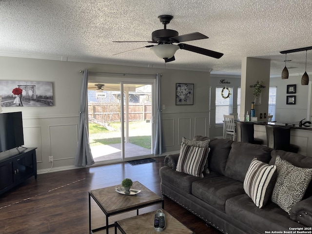 living area with a decorative wall, ornamental molding, and a healthy amount of sunlight