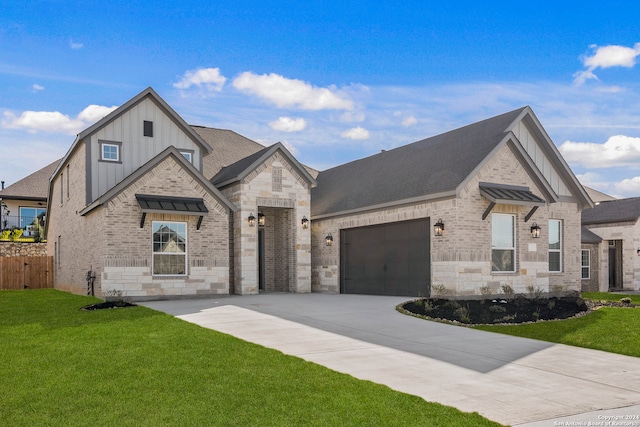 french country home featuring board and batten siding, concrete driveway, a front yard, and brick siding