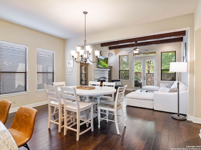 dining space featuring ceiling fan with notable chandelier, baseboards, beam ceiling, and dark wood finished floors