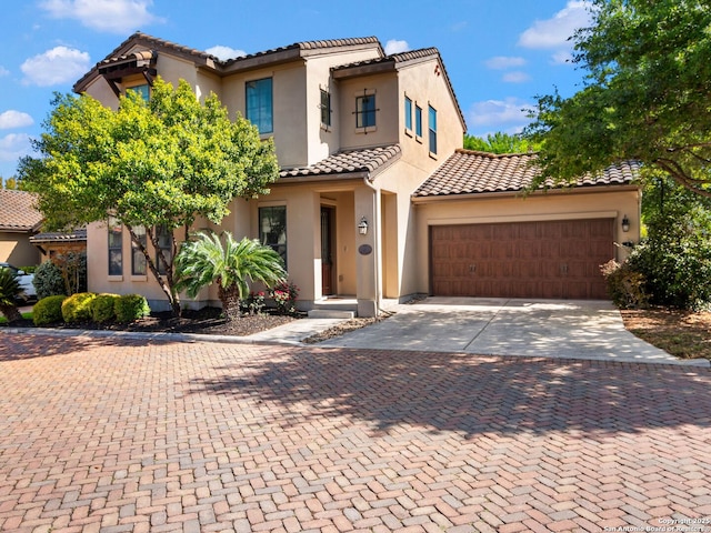 mediterranean / spanish house with a tiled roof, a garage, driveway, and stucco siding