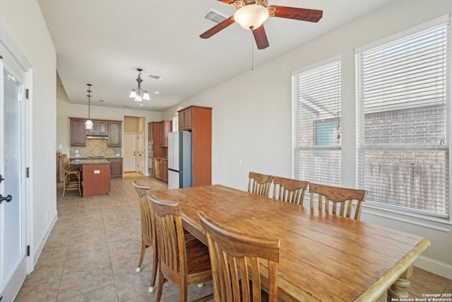 dining room featuring ceiling fan with notable chandelier, light tile patterned flooring, baseboards, and visible vents