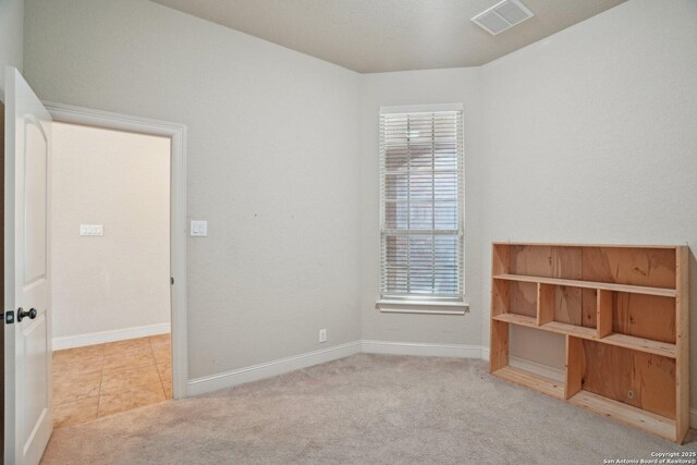 carpeted spare room with baseboards, visible vents, and plenty of natural light