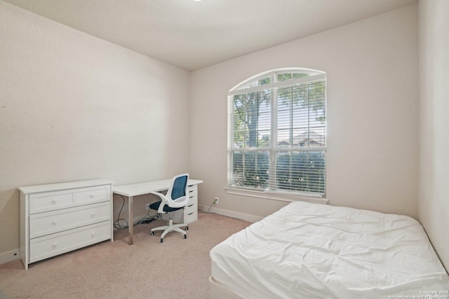 bedroom with light colored carpet and baseboards