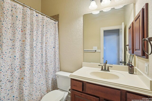 full bath with toilet, a textured wall, vanity, and a shower with curtain