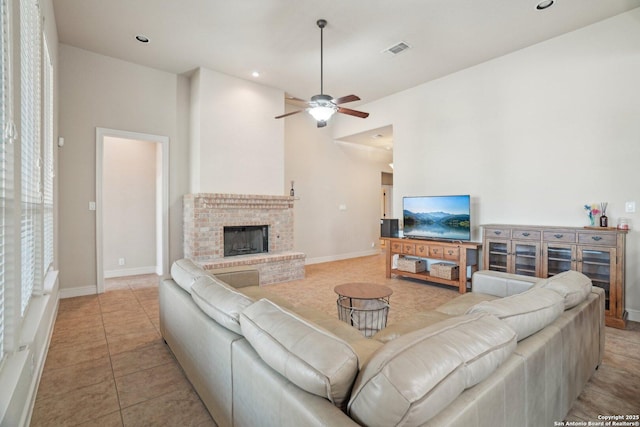 living area with baseboards, ceiling fan, a fireplace, and visible vents