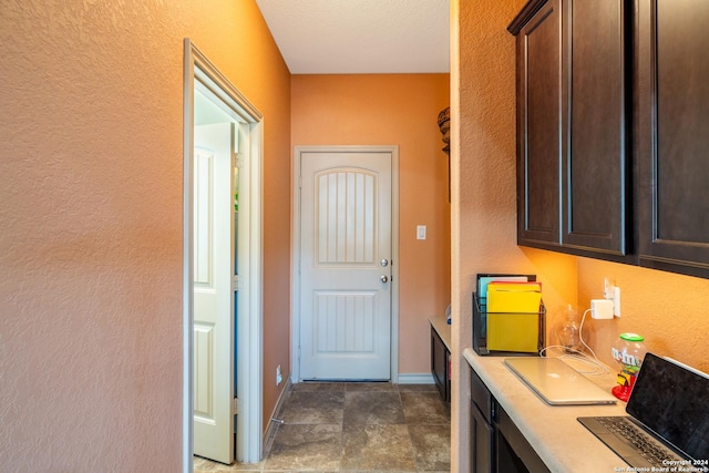 interior space with a textured wall, stone finish floor, and baseboards