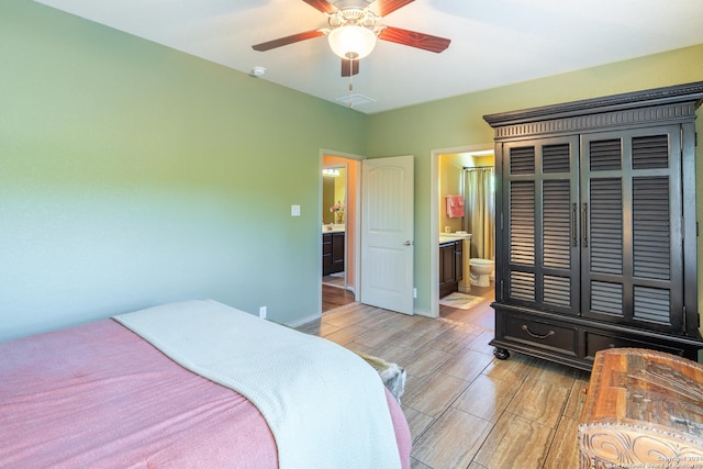 bedroom featuring visible vents, baseboards, ceiling fan, light wood-style floors, and ensuite bath