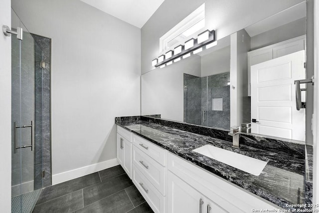 full bath with a shower stall, a sink, tile patterned floors, double vanity, and baseboards