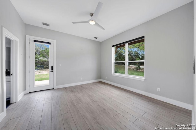 unfurnished room with light wood-style floors, baseboards, a ceiling fan, and visible vents