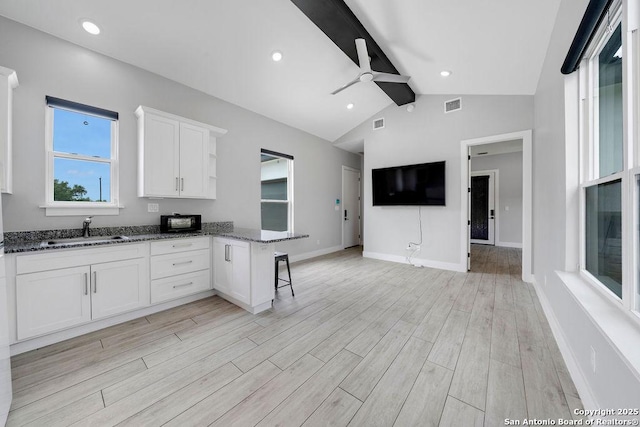 kitchen with a sink, white cabinets, a ceiling fan, and light wood-style flooring