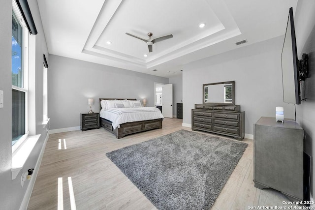 bedroom featuring visible vents, recessed lighting, wood finished floors, a raised ceiling, and baseboards