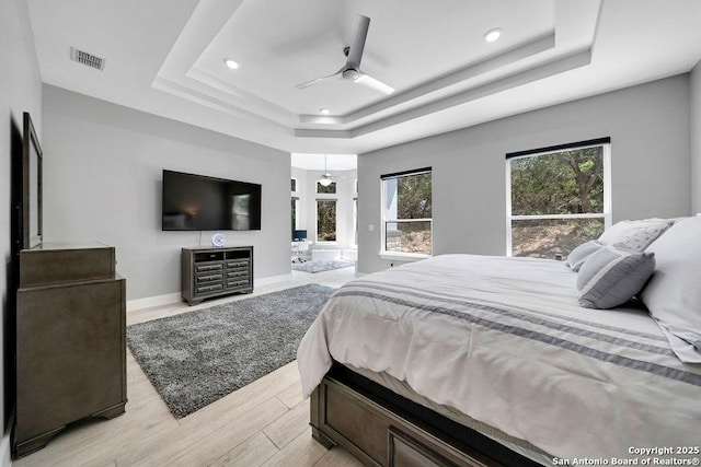 bedroom with baseboards, recessed lighting, light wood-style floors, visible vents, and a raised ceiling
