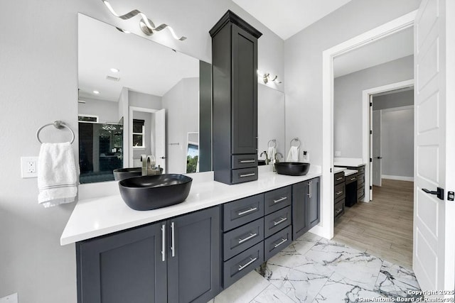full bathroom with marble finish floor, double vanity, a sink, and walk in shower