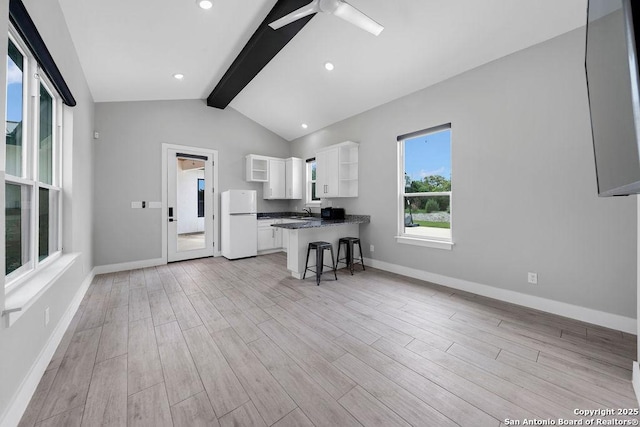 kitchen featuring open shelves, lofted ceiling with beams, dark countertops, freestanding refrigerator, and white cabinetry