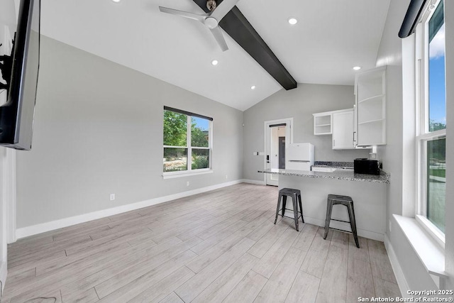kitchen featuring a ceiling fan, freestanding refrigerator, open shelves, light wood-style floors, and vaulted ceiling with beams