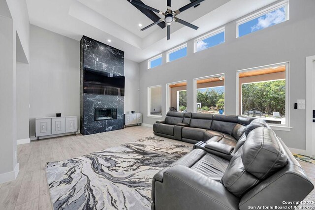 living room with plenty of natural light, a towering ceiling, ceiling fan, and wood finished floors