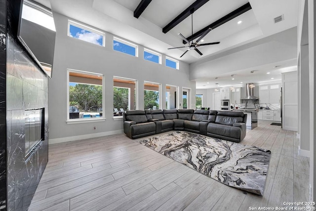living room featuring light wood finished floors, beamed ceiling, a ceiling fan, and visible vents
