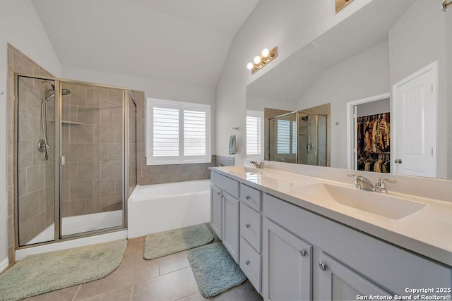 bathroom featuring a sink, a shower stall, double vanity, vaulted ceiling, and tile patterned floors