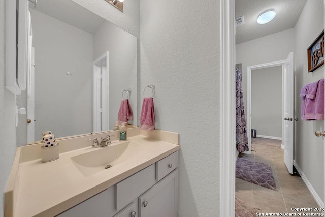 bathroom featuring vanity, a textured wall, tile patterned flooring, and visible vents