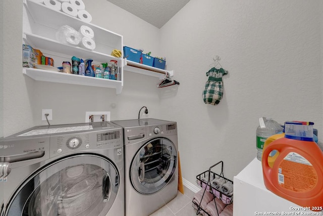 clothes washing area with laundry area, light tile patterned floors, independent washer and dryer, a textured ceiling, and baseboards