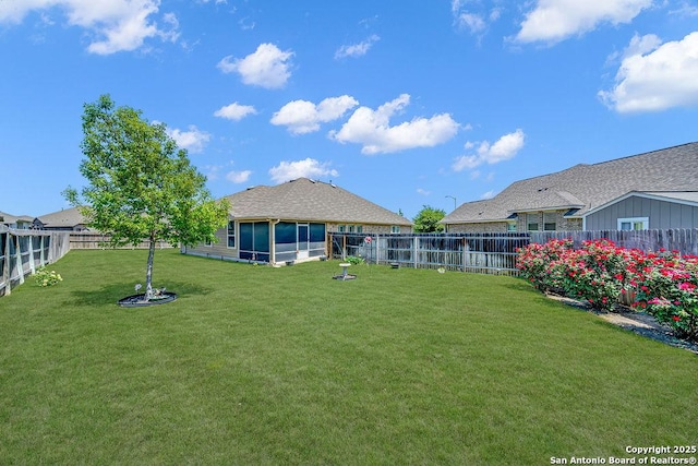 rear view of house with a fenced backyard and a lawn