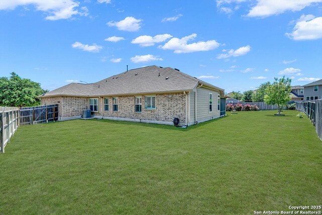rear view of house with a yard, brick siding, a fenced backyard, and central AC unit