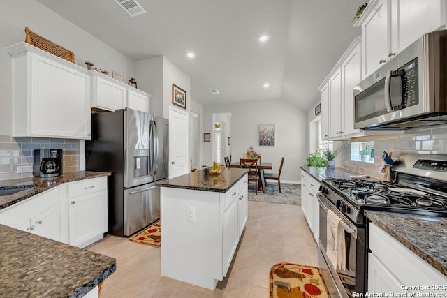 kitchen featuring white cabinets, recessed lighting, vaulted ceiling, a kitchen island, and appliances with stainless steel finishes