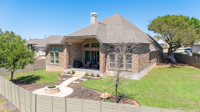 581 Vale Ct, New Braunfels, TX 78132 - rear view of house featuring a chimney, brick siding, a fenced backyard, a yard, and a shingled roof