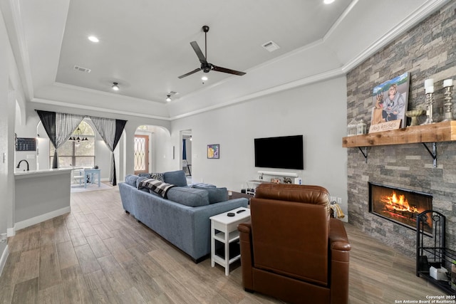 291 Strasbourg, Castroville, TX 78009 - living room with a raised ceiling, ceiling fan, a fireplace, wood finished floors, and ornamental molding