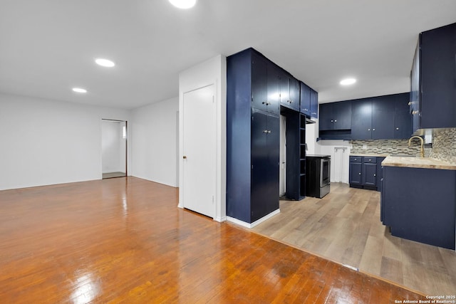162 Birchwood, San Antonio, TX 78213 - kitchen featuring light countertops, light wood finished floors, stainless steel range with electric cooktop, backsplash, and blue cabinetry