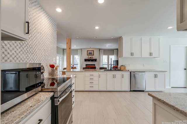 kitchen featuring appliances with stainless steel finishes, white cabinetry, recessed lighting, backsplash, and light stone counters