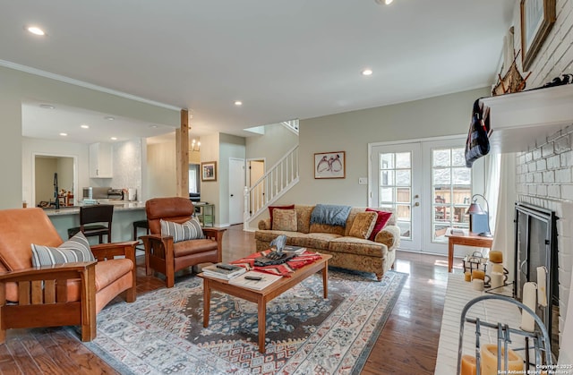 living room featuring a fireplace, crown molding, recessed lighting, stairway, and wood finished floors