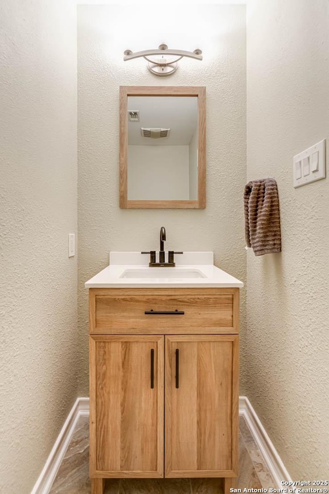 bathroom featuring visible vents, baseboards, and vanity