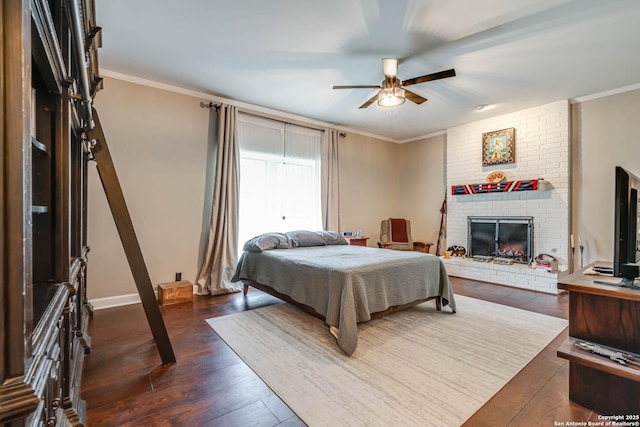 bedroom featuring baseboards, a brick fireplace, ornamental molding, a ceiling fan, and dark wood-type flooring