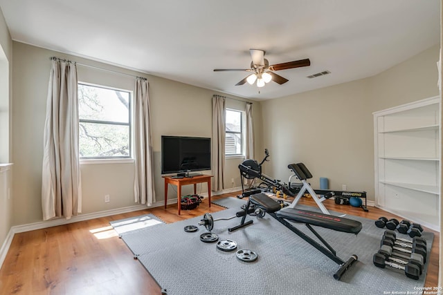 workout area featuring light wood-style flooring, visible vents, ceiling fan, and baseboards