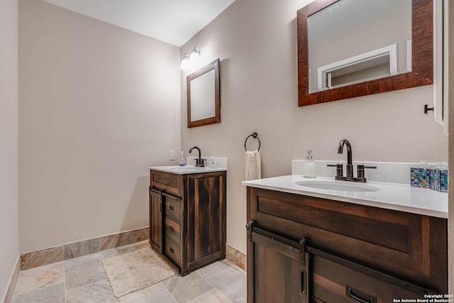 bathroom with two vanities, baseboards, and a sink