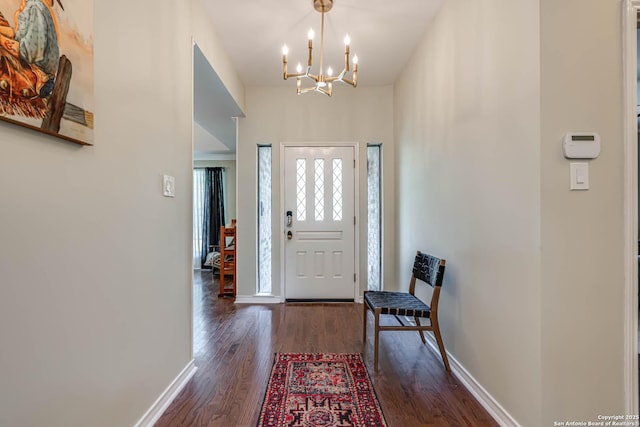 entryway with dark wood-style flooring, baseboards, and an inviting chandelier