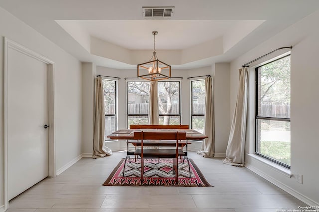 interior space featuring a tray ceiling, an inviting chandelier, baseboards, and visible vents