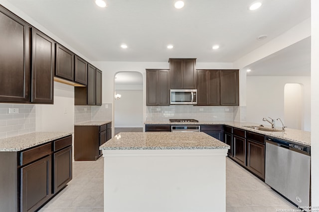 29991 Jove, Bulverde, TX 78163 - kitchen featuring dark brown cabinetry, light stone countertops, appliances with stainless steel finishes, arched walkways, and a sink
