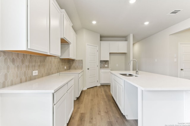 10214 King Robert, San Antonio, TX 78239 - kitchen with a sink, light wood finished floors, white cabinets, recessed lighting, and a center island with sink