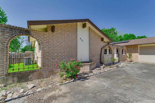 view of property exterior with brick siding, fence, and a garage